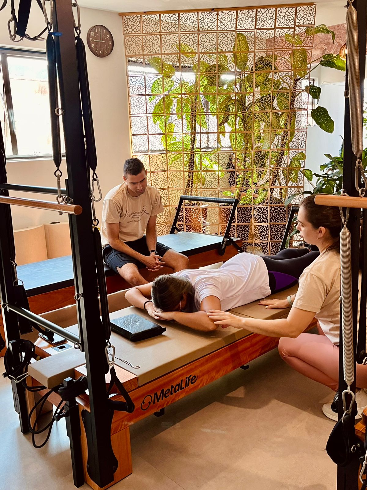 Atendimento de pilates com aluna sendo acompanhada por profissionais da Clínica Inspirar